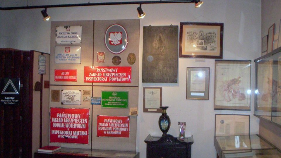 Expozícia krakovského múzea poistenia s tabuľkami poisťovní na stene